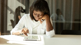 IT student studying on a tablet in a modern workspace, representing learning through an information technology online course.