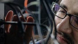 IT professional configuring network cables and systems, representing hands-on training in networking courses online at Level 5.