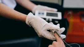 Healthcare professional wearing gloves and handling medical equipment, representing practical care and safety skills taught in a Level 5 health and social care course.