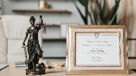 Statue of Lady Justice beside a framed legal certificate, representing advanced legal studies in a Level 5 diploma in law.