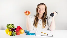 Nutrition expert holding a grapefruit and dumbbell beside fresh produce, illustrating advanced Diet and Nutrition Level 7 training.