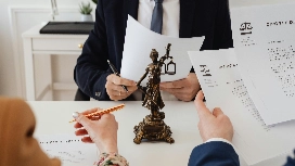 Legal professionals reviewing documents with Lady Justice statue, representing level 7 international business law diploma courses