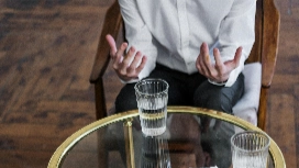 Person seated in a coaching session, using expressive hand gestures, symbolising guidance, self-development and supportive life coaching conversations.