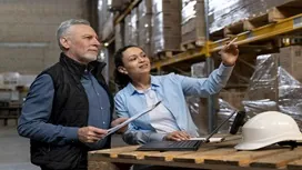 Two supply chain professionals inspect warehouse inventory and review documents, illustrating effective supplier performance management.