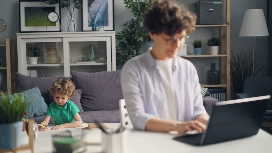 Remote worker using a laptop at home while caring for a child, demonstrating effective work-life balance skills