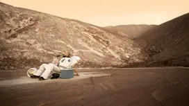 Person in a futuristic astronaut suit relaxing on a surreal desert-like landscape, illustrating the creative visuals generated with MidJourney AI.