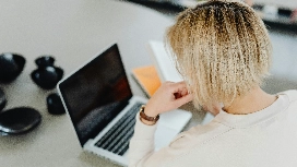 Person working on a laptop with documents beside them, representing essential digital and office productivity skills taught in MS Office courses.