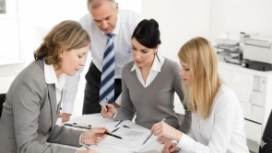 Professionals discussing documents in a meeting, illustrating negotiation skills, communication and collaboration techniques
