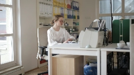 Office administrator working at a desk with files and documents, representing organisational and clerical skills taught in office administration courses.