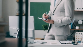 Administrative professional reviewing documents and taking notes in an office, demonstrating administrative assistant abilities and organisation skills