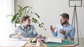 Two professionals engaged in a thoughtful discussion at a desk, symbolizing persuasion skills and AI-supported communication strategies.