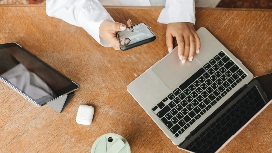 Professional using a laptop and smartphone with remote workforce tools to improve productivity and collaboration