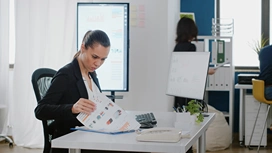 Professional reviewing project charts at an office desk for an online planning and scheduling professional course
