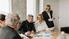 A team of professionals reviewing charts and documents together, representing analytical thinking and collaboration in problem-solving courses.