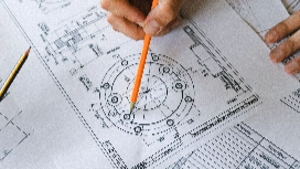 Hand reviewing detailed technical drawings and diagrams, representing prompt engineering skills and structured AI instruction design