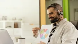 A remote customer service professional wearing a headset explains a chart during an online session, representing remote customer service training.