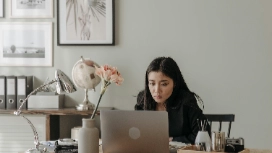 Woman working remotely at a home desk with a laptop, representing essential skills for effective remote work and digital collaboration