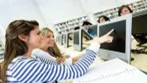 Students collaborating at computer workstations in a modern learning environment, representing advanced retail management training and strategic skills development.