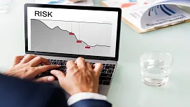 A professional reviewing a declining risk chart on a laptop, illustrating fundamental concepts taught in introductory Level 1 risk management courses.