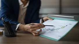A project manager reviewing a printed workflow diagram on a clipboard, representing scope definition and structured project planning processes.