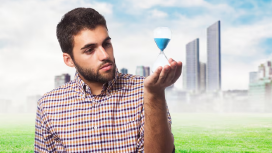 A man thoughtfully observing an hourglass outdoors, symbolizing self-reflection, personal growth, and the process of improving self-esteem.