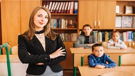 A teacher standing confidently in a classroom with students seated behind her, reflecting advanced SEN support and leadership taught in Level 7 SEN teaching assistant diplomas.