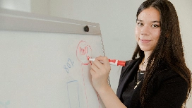 Woman writing a growth plan on a whiteboard, representing setting personal development goals in leadership training.