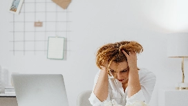 Office worker showing signs of stress while working at a laptop, illustrating emotional wellbeing and stress management