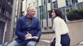 Two professionals having a calm conversation outdoors, symbolizing emotional support, communication and coping strategies in stress management courses.