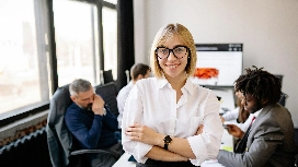 Confident business professional standing before her team, symbolizing leadership development and future planning taught in succession planning courses.
