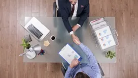 Two professionals shaking hands across a desk during a business meeting, illustrating key concepts of supplier relationship management.