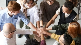 Diverse team joining hands in a circle, symbolizing collaboration, inclusive hiring practices and effective talent acquisition management in HR.