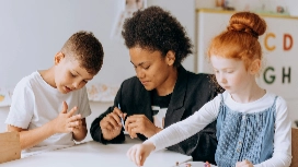 Teaching assistant guiding young children in classroom activity – teaching assistant short course online with OHSC