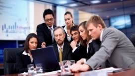 Professionals collaborating around a laptop, illustrating teamwork skills, communication and effective team working abilities