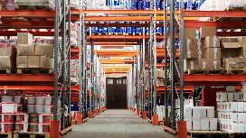 Wide warehouse aisles with stocked racks and pallets – learn warehousing & material handling skills online with OHSC.