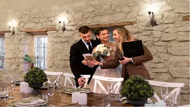 Bride and groom reviewing plans with a wedding planner in a decorated venue, illustrating professional coordination and event planning skills.