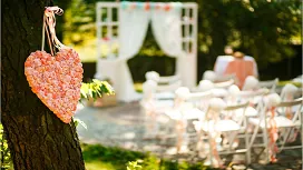 Outdoor wedding ceremony setup with floral heart décor, white chairs, and a decorated arch, representing beginner wedding planning skills.