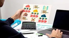 A person reviewing colorful project timeline graphics beside a laptop and calculator, representing how Gantt charts support project scheduling.